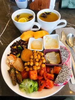 A plate from the buffet: kimchi, chickpeas, black beans, dragon fruit and mango, with tea.