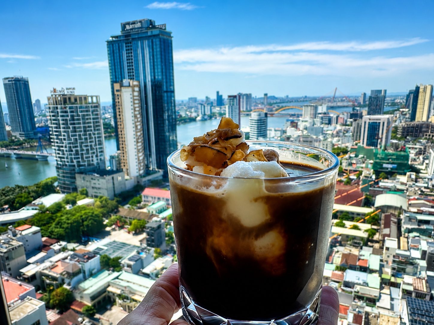 Iced coffee from the Club Lounge, 24th floor — the Han River and the Dragon Bridge behind it. Our own photo.
